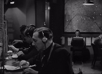 Movie still from “Mad Love” (1935), directed by Karl Freund – A group of people sitting at a table with headphones on; Medium shot, High angle