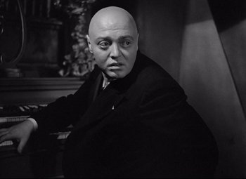 Movie still from “Mad Love” (1935), directed by Karl Freund – A man with a bald head sitting in front of a piano; Close Up shot, Low angle