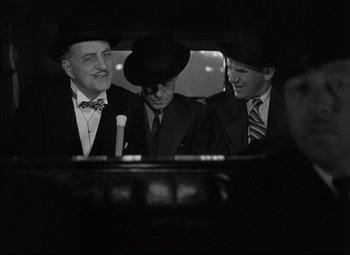 Movie still from “Mad Love” (1935), directed by Karl Freund – A group of men sitting in the back of a car; Medium shot, Over the shoulder angle