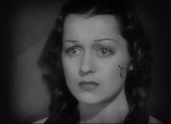 Movie still from “Mad Love” (1935), directed by Karl Freund – An old photo of a woman with a cross on her face; Close Up shot, High angle