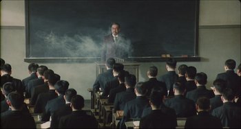 Movie still from “Madadayo” (1993), directed by Akira Kurosawa – A man standing in front of a group of people; Wide shot, High angle