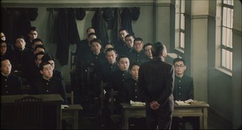 Movie still from “Madadayo” (1993), directed by Akira Kurosawa – A group of men in uniform sitting in a room; Wide shot, High angle