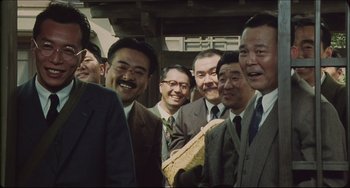 Movie still from “Madadayo” (1993), directed by Akira Kurosawa – A group of men standing next to each other in suits; Medium shot, Low angle