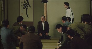 Movie still from “Madadayo” (1993), directed by Akira Kurosawa – A group of people sitting on steps in front of a wall; Wide shot, High angle