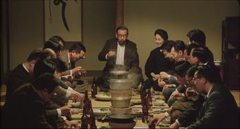Movie still from “Madadayo” (1993), directed by Akira Kurosawa – A group of people sitting around a dinner table; Medium shot, High angle