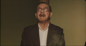 Movie still from “Madadayo” (1993), directed by Akira Kurosawa – An older man wearing glasses and a jacket; Medium shot, Low angle
