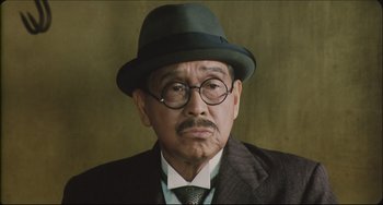 Movie still from “Madadayo” (1993), directed by Akira Kurosawa – An older man wearing a hat and glasses; Close Up shot, Low angle