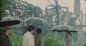 Movie still from “Madadayo” (1993), directed by Akira Kurosawa – A group of people standing next to each other holding umbrellas; Extreme Wide shot, Low angle
