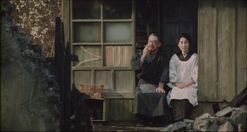 Movie still from “Madadayo” (1993), directed by Akira Kurosawa – An older man and woman sitting on a bench; Medium shot, High angle