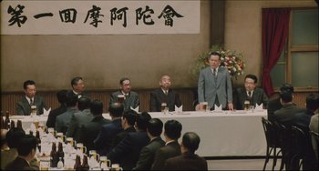 Movie still from “Madadayo” (1993), directed by Akira Kurosawa – A group of people sitting at a table with papers; Wide shot, High angle