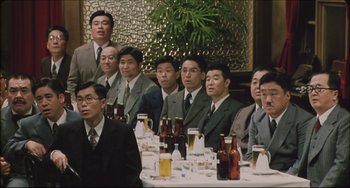 Movie still from “Madadayo” (1993), directed by Akira Kurosawa – A group of men sitting at a table with beer; Medium shot, High angle