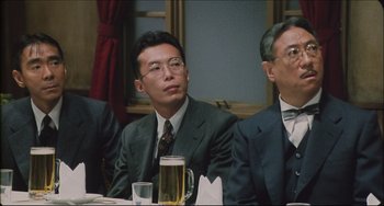 Movie still from “Madadayo” (1993), directed by Akira Kurosawa – A group of men sitting at a table with a beer; Medium shot, Low angle
