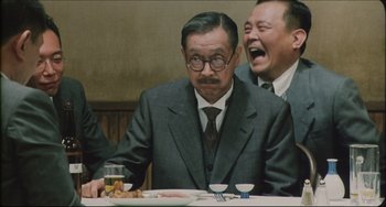 Movie still from “Madadayo” (1993), directed by Akira Kurosawa – Two men in suits sitting at a dinner table; Medium shot, Over the shoulder angle