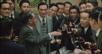 Movie still from “Madadayo” (1993), directed by Akira Kurosawa – A group of men standing around each other at a party; Medium shot, High angle