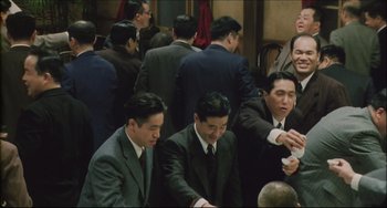 Movie still from “Madadayo” (1993), directed by Akira Kurosawa – A group of men standing around each other in a room; Medium shot, High angle