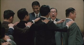 Movie still from “Madadayo” (1993), directed by Akira Kurosawa – A group of men standing next to each other in a room; Medium shot, Low angle