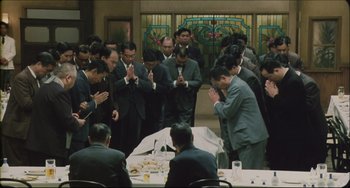 Movie still from “Madadayo” (1993), directed by Akira Kurosawa – A group of men standing around a table with food; Wide shot, High angle