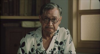 Movie still from “Madadayo” (1993), directed by Akira Kurosawa – An older man wearing glasses and a floral shirt; Close Up shot, Over the shoulder angle