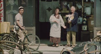 Movie still from “Madadayo” (1993), directed by Akira Kurosawa – A man and a woman holding a white cat; Wide shot, Low angle