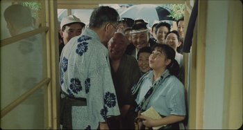 Movie still from “Madadayo” (1993), directed by Akira Kurosawa – A group of people gathered around a man wearing a hawaiian shirt; Medium shot, High angle