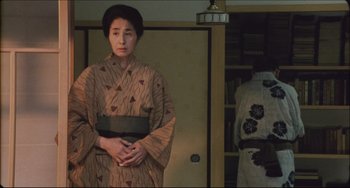 Movie still from “Madadayo” (1993), directed by Akira Kurosawa – A woman in a kimono standing in front of a doorway; Medium shot, Low angle