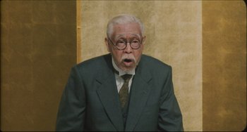 Movie still from “Madadayo” (1993), directed by Akira Kurosawa – An older man wearing a suit and tie; Medium shot, Low angle