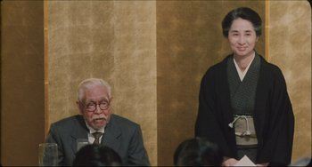 Movie still from “Madadayo” (1993), directed by Akira Kurosawa – A man and a woman sitting next to each other in a room; Medium shot, Low angle