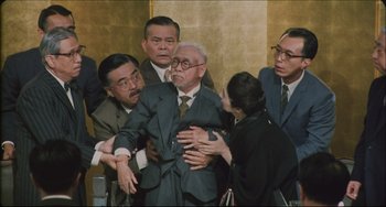 Movie still from “Madadayo” (1993), directed by Akira Kurosawa – A group of men and women in suits and ties; Medium shot, High angle