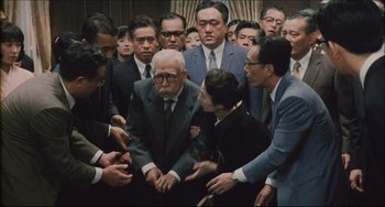 Movie still from “Madadayo” (1993), directed by Akira Kurosawa – A group of people gathered around an older man; Medium shot, High angle