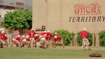 Movie still from “Made” (2001), directed by Jon Favreau – A group of football players in a field; Extreme Wide shot, High angle