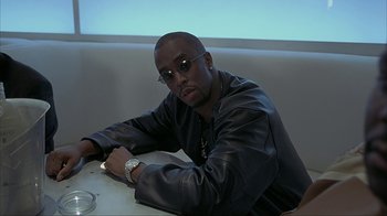 Movie still from “Made” (2001), directed by Jon Favreau – A man sitting at a table in front of a blue screen; Medium shot, Low angle