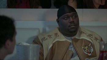 Movie still from “Made” (2001), directed by Jon Favreau – A person sitting in a chair wearing a hat; Close Up shot, High angle