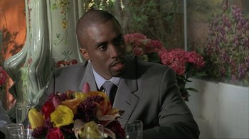 Movie still from “Made” (2001), directed by Jon Favreau – A man sitting at a table with a bouquet of flowers in front of him; Close Up shot, Over the shoulder angle