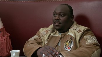 Movie still from “Made” (2001), directed by Jon Favreau – A man sitting at a table in front of a red wall; Close Up shot, Low angle