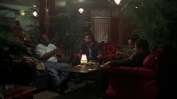Movie still from “Made” (2001), directed by Jon Favreau – A group of people sitting around a table in a room; Wide shot, High angle
