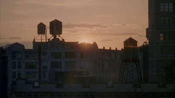 Movie still from “Made” (2001), directed by Jon Favreau – The sun is setting over a building with water towers in the background; Extreme Wide shot, Low angle