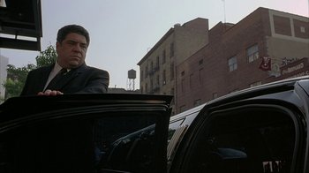 Movie still from “Made” (2001), directed by Jon Favreau – A man standing next to a car in a city; Medium shot, Low angle