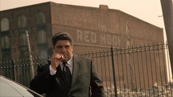 Movie still from “Made” (2001), directed by Jon Favreau – A man in a suit and tie smoking a cigarette; Medium shot, Low angle