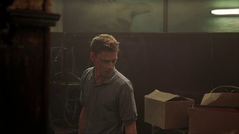 Movie still from “Made” (2001), directed by Jon Favreau – A man standing in front of a window in a dark room; Medium shot, Low angle