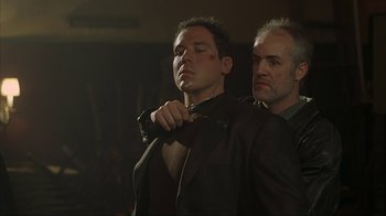 Movie still from “Made” (2001), directed by Jon Favreau – A man in a black jacket is being held by another man; Close Up shot, Over the shoulder angle