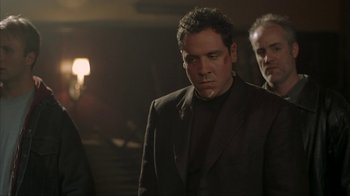 Movie still from “Made” (2001), directed by Jon Favreau – A group of men standing next to each other in a dark room; Medium shot, Over the shoulder angle