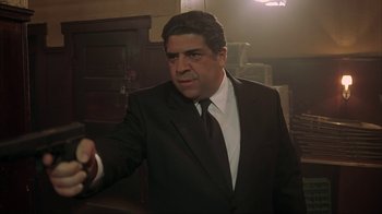 Movie still from “Made” (2001), directed by Jon Favreau – A man wearing a suit and tie holding something; Medium shot, Low angle