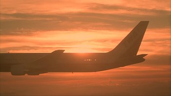 Movie still from “Made” (2001), directed by Jon Favreau – An airplane is flying in the sky during a sunset; Extreme Wide shot, Low angle