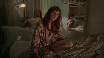 Movie still from “Made” (2001), directed by Jon Favreau – A woman sitting on top of a bed wearing a robe; Medium shot, High angle