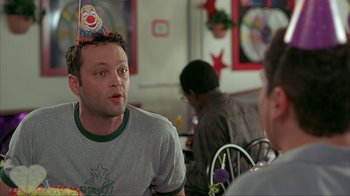 Movie still from “Made” (2001), directed by Jon Favreau – A man wearing a birthday party hat in a restaurant; Medium shot, Over the shoulder angle
