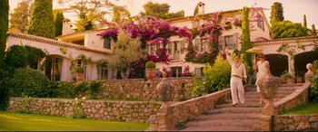Movie still from “Magic in the Moonlight” (2014), directed by Woody Allen – A stone wall and steps leading up to a house with flowers growing on it; Extreme Wide shot, High angle