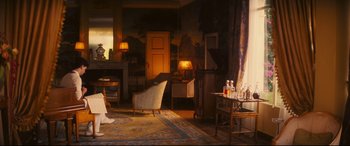 Movie still from “Magic in the Moonlight” (2014), directed by Woody Allen – A living room filled with furniture next to a fire place; Wide shot, Over the shoulder angle