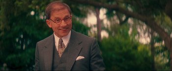 Movie still from “Magic in the Moonlight” (2014), directed by Woody Allen – A man in a suit and tie smiling for the camera; Close Up shot, Over the shoulder angle