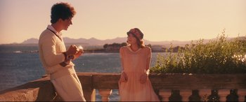 Movie still from “Magic in the Moonlight” (2014), directed by Woody Allen – A woman in a pink dress standing next to another woman in a pink dress; Medium shot, Over the shoulder angle