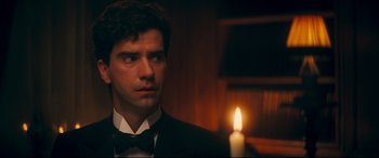 Movie still from “Magic in the Moonlight” (2014), directed by Woody Allen – A man in a suit and bow tie looking at a candle; Close Up shot, Over the shoulder angle